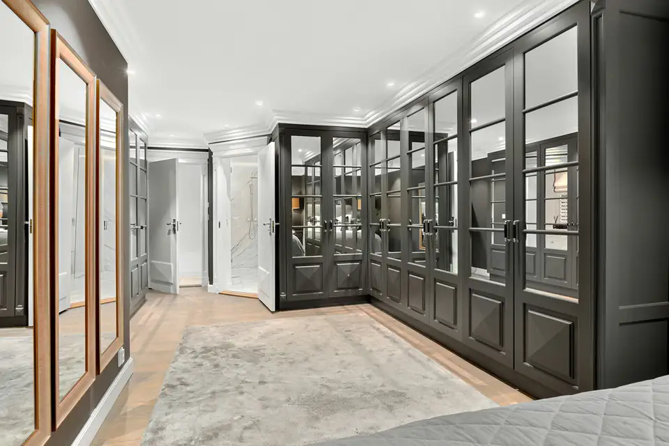 Black-framed glazed wardrobes running the length of a dressing room, a fitted wardrobe idea for Newcastle homes