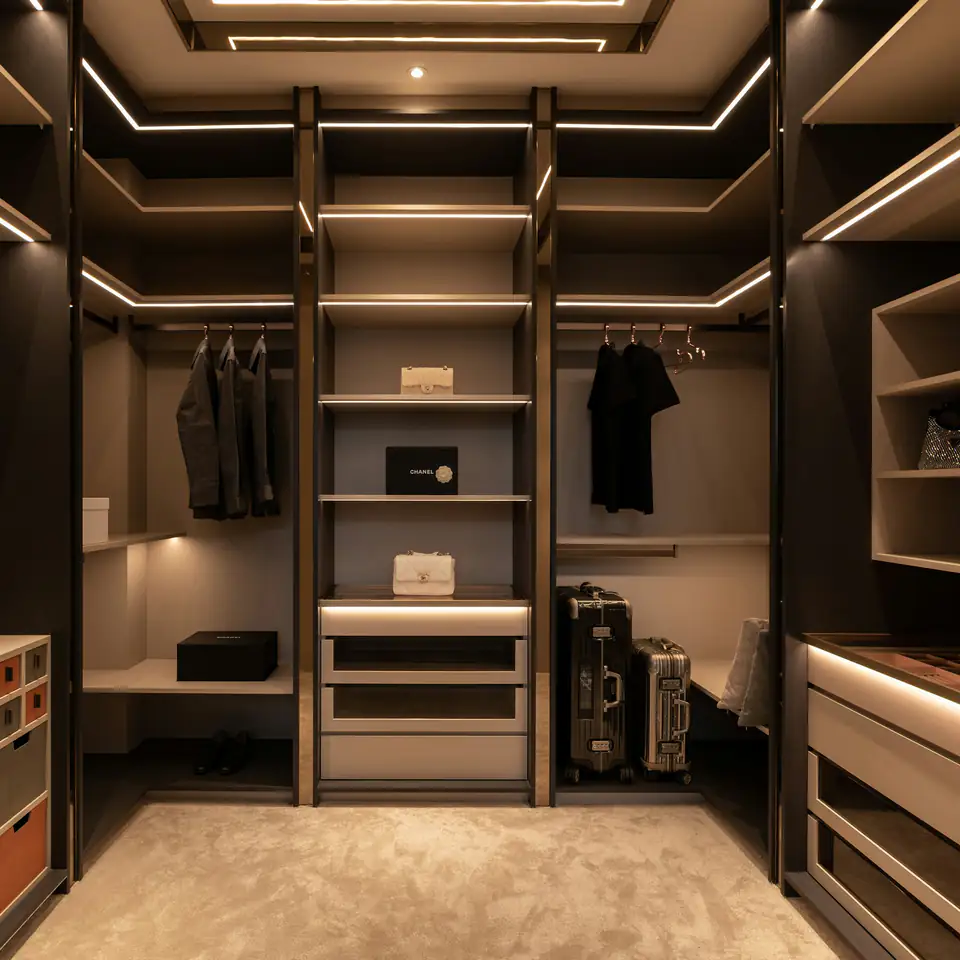 Dark walk-in wardrobe with warm LED-lit shelves and drawers, a fitted wardrobe idea for Newcastle homes