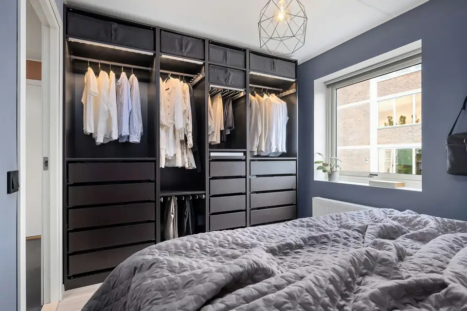 Open-fronted dark wardrobe system in a bedroom beside a window, design inspiration for bedrooms in Newcastle